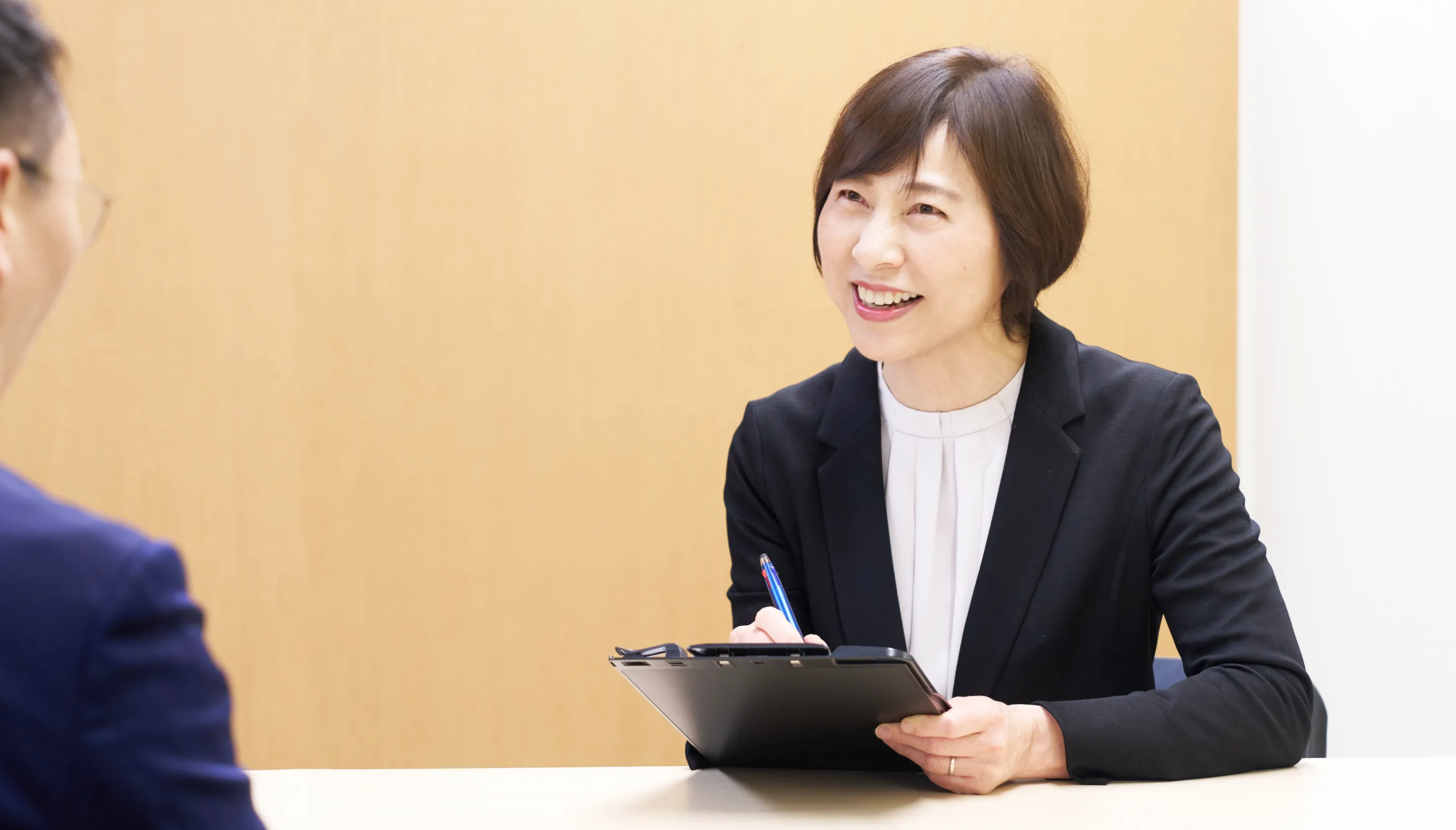 クライアントの話を笑顔で聞く女性コンサルタント
